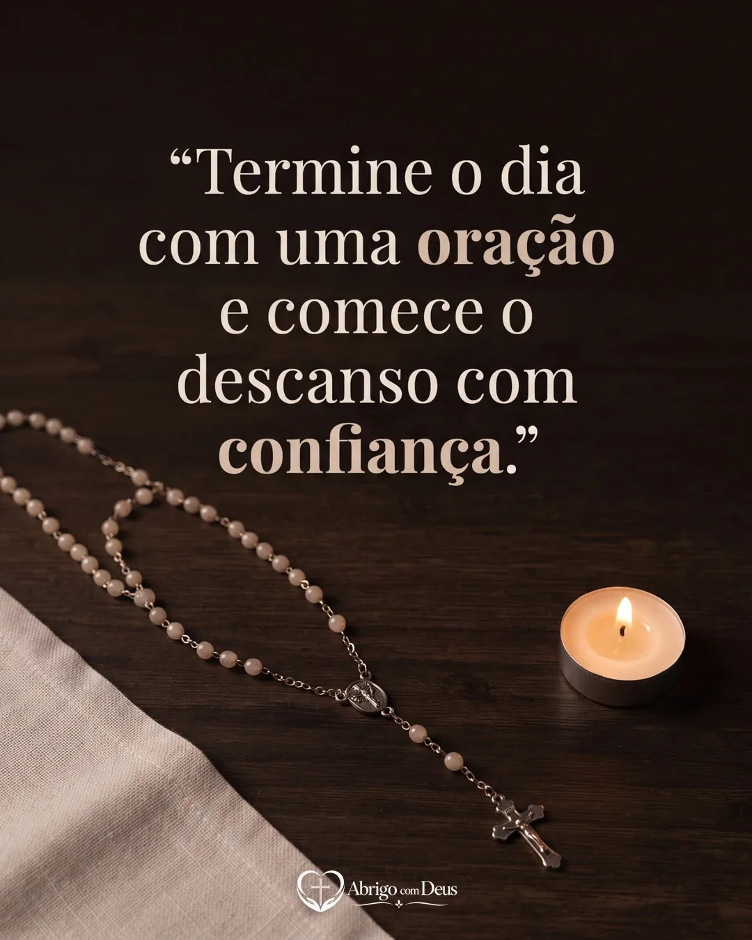 Cartão com terço e pequena vela acesa sobre mesa de madeira escura e mensagem para terminar o dia com oração e confiança.